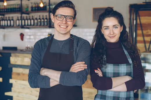 Two shop owners standing at the counter of their cafe.